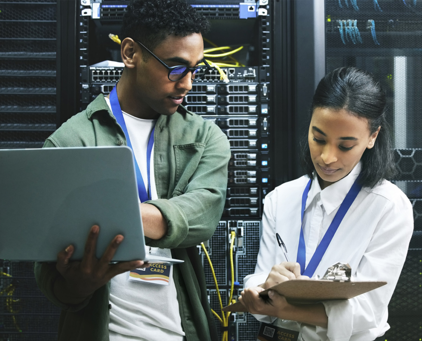 Front view of two IT professionals looking at clipboard together in server room